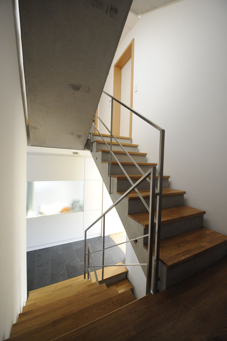 Beton-Treppe mit Edelstahl-Geländer und hochwertigem Parkett-Boden